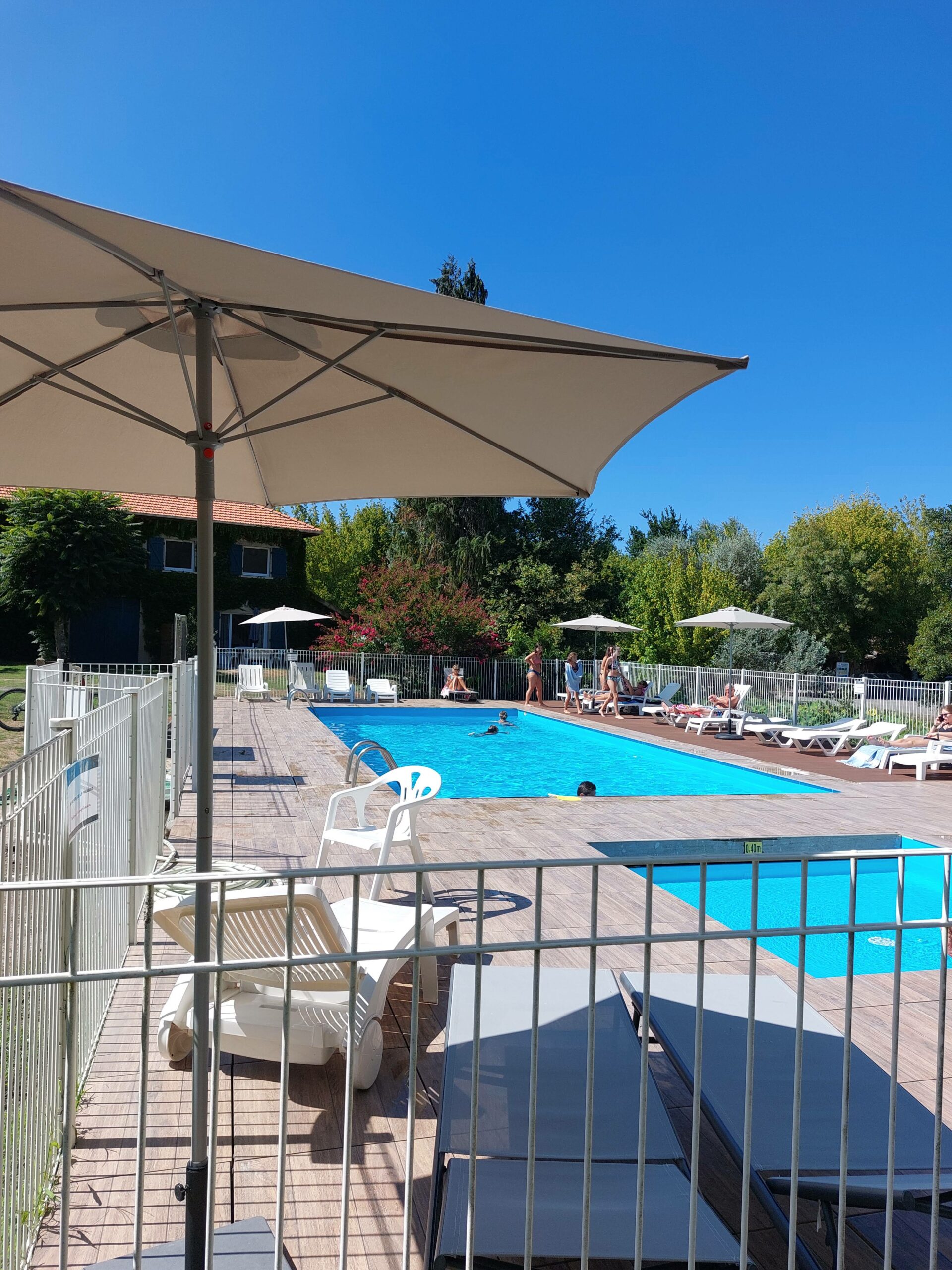 Grande piscine de camping avec transats et parasols sous ciel bleu
